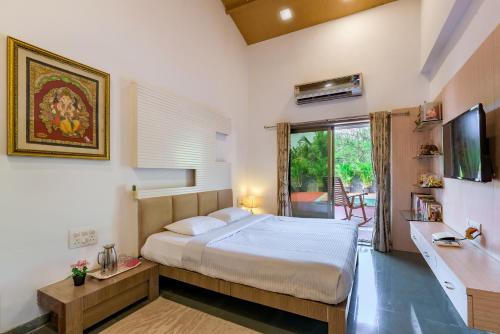 a bedroom with a bed and a television in it at SaffronStays Adora Woods & Hills, Luxury Pool Villa in Murud in Jambrung 