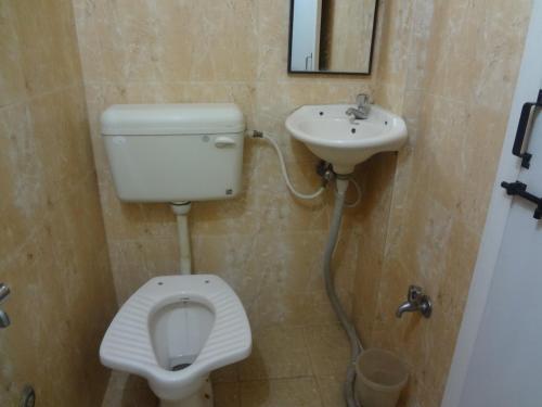 a bathroom with a toilet and a sink at Hotel Rajmandir in Pune