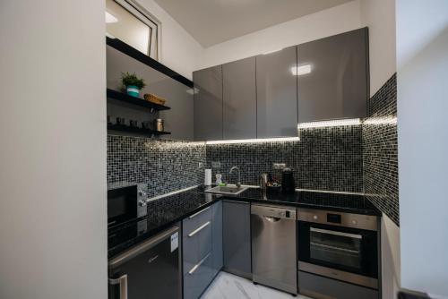 eine Küche mit Küchengeräten aus Edelstahl und schwarzen Fliesen in der Unterkunft Jacks's Home apartman - free parking in Pécs