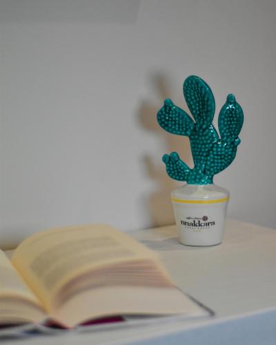 a plant in a cup next to an open book at Nnakkara Guest House in Santo Stefano di Camastra