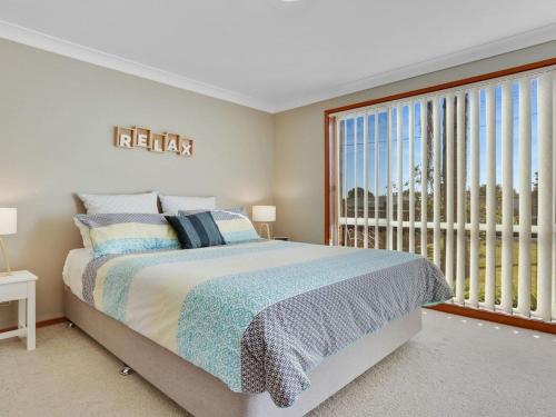 1 dormitorio con cama grande y ventana grande en Cleveland Place, en Culburra Beach