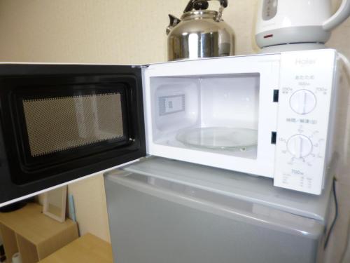 a microwave oven sitting on top of a refrigerator at ザミッキーカールトン井尻102 in Shiobaru