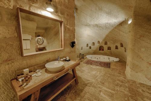 a stone bathroom with a sink and a tub at Solem Cave Suites in Urgup