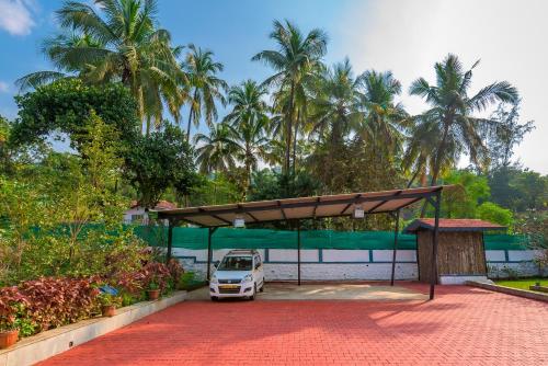 a parking lot with a white car under a canopy at SaffronStays Adora Woods & Hills, Luxury Pool Villa in Murud in Jambrung 