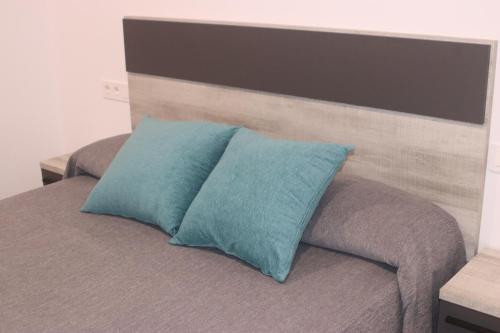 a bed with two blue pillows on top of it at APARTAMENTOS AGUAMARINA in Peniscola