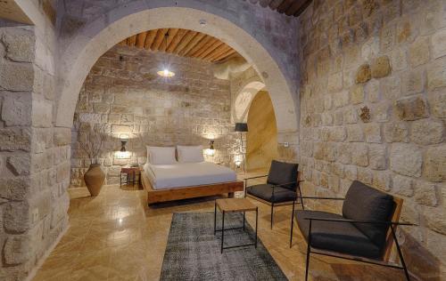 a bedroom with a bed and chairs in a stone wall at Solem Cave Suites in Urgup