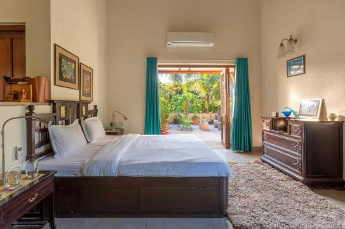 a bedroom with a large bed and a sliding glass door at Villa Amaaya - The Hidden Gem by StayVista in Alibaug