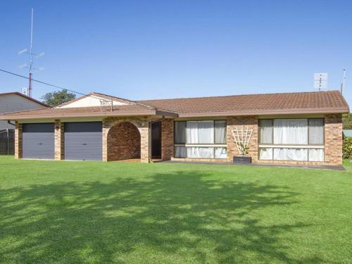 Una casa con un césped verde delante de ella. en Beachway, en Culburra Beach