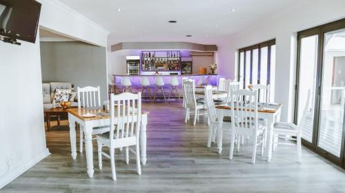 un comedor con mesas blancas y sillas blancas en Victoria & Alfred Boutique Hotel en Puerto Elizabeth