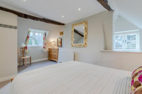 a bedroom with a white bed and a mirror at Corner Cottage in Bretforton