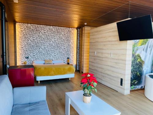 Habitación con cama, sofá y TV. en Cabañas Fisterra, en Finisterre