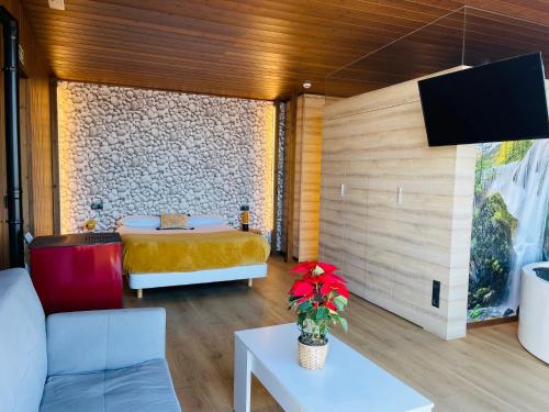 フィステーラにあるCabañas Fisterraのベッド、ソファ、テレビが備わる客室です。