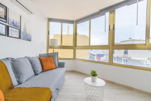 un salon avec un canapé et quelques fenêtres dans l'établissement Home2Book Design Las Canteras2 Beach, à Las Palmas de Gran Canaria
