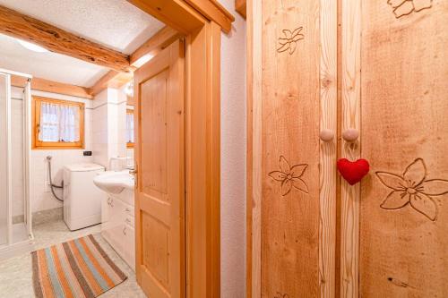 a bathroom with a wooden wall with a heart on it at Charming Tabià in Rocca Pietore