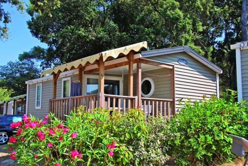 a tiny house with a porch in a yard at Camping Parc Mogador in Sanary-sur-Mer