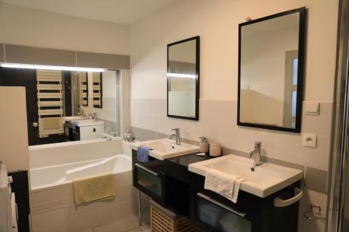 ein Badezimmer mit zwei Waschbecken und einem großen Spiegel in der Unterkunft Maison charmante à Arques-la-Bataille avec terrasse et cheminée. in Arques-la-Bataille