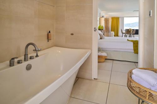 a bathroom with a bath tub and a bedroom at L'Escale Côté Sud in LʼÎle-Rousse