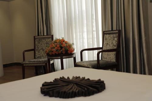 a table with two chairs and a vase of flowers on it at Base Ethiopia International Hotel in Addis Ababa