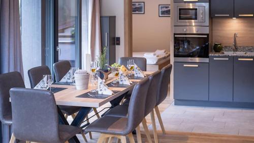 a dining room table with chairs and a kitchen at Sunny Ferienwohnungen Ski In - Ski Out - Self Check-in in Zell am See