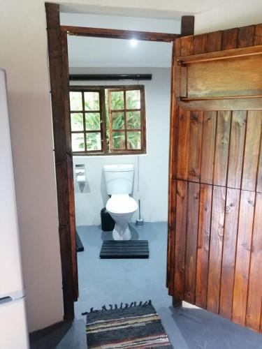 a bathroom with a toilet and a wooden door at Ikaya Accommodation PSJ in Port St Johns