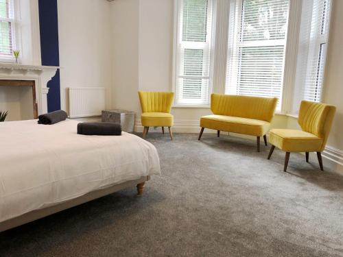 ein Schlafzimmer mit 2 Stühlen, einem Bett und einem Kamin in der Unterkunft Summer Breeze. 3-bed apartment close to the beach in Bournemouth