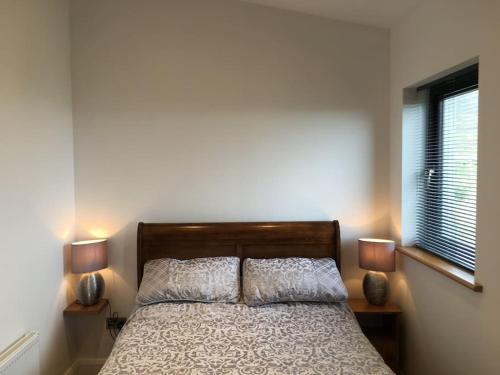1 dormitorio con 1 cama con 2 lámparas y una ventana en Silver Strand Chalets en Glencolumbkille
