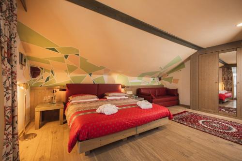 a bedroom with a large bed with a red blanket at Hotel Rubino Deluxe in Campitello di Fassa