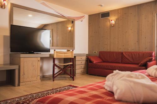a hotel room with a television and a couch at Hotel Rubino Deluxe in Campitello di Fassa