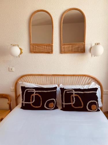 a bedroom with a bed with two mirrors on the wall at Hôtel Le Britannic - centre gare- in Saint Malo