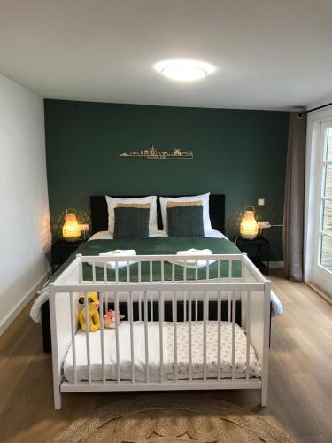 a white crib in a bedroom with a green wall at De Haarlemse Logeerkamer in Haarlem