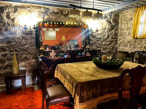 Αρχοντικό Βογιάρου في كالاريتيس: غرفة طعام مع طاولة وجدار حجري