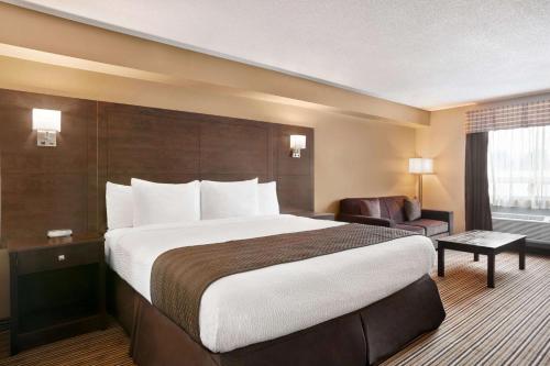 a hotel room with a large bed and a chair at Days Inn by Wyndham Leamington in Leamington
