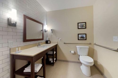 een badkamer met een toilet, een wastafel en een spiegel bij Comfort Inn & Suites Harrah 