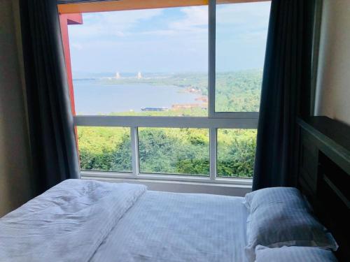 Bett in einem Zimmer mit einem großen Fenster in der Unterkunft lovely 2-bedroom sea view serviced apartment dabolim goa in Dabolim