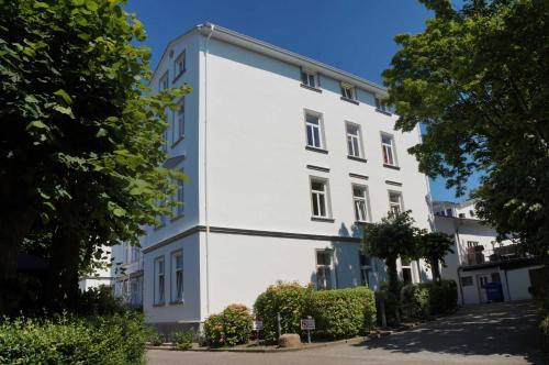 ゲーレンにあるKurhaus Nordstrand Fewo 46003の前に木々がある白い建物