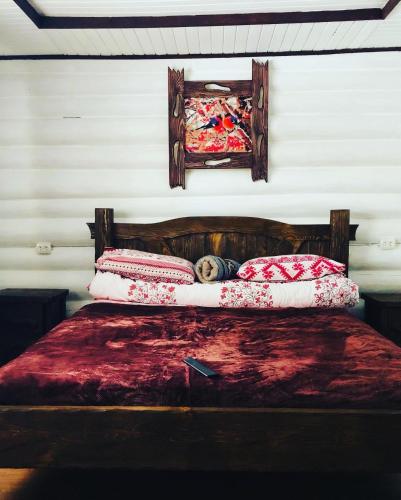 a bed with a wooden headboard and pillows on it at У Віти котедж 1 in Synevyrsʼka Polyana