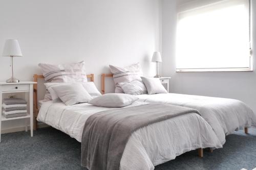 a white bedroom with two beds and a window at Ferienwohnung Speldorf in Mülheim an der Ruhr