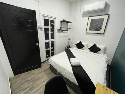 a bedroom with a bed with white sheets and a black door at The Sky Inn in Kuantan