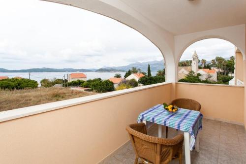 a balcony with a table and chairs and a view of the water at Apartments Ana Lopud in Lopud Island