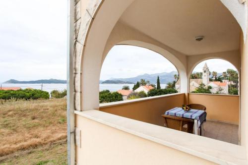 Une porte ouverte s'ouvre sur un balcon offrant une vue sur l'eau. dans l'établissement Apartments Ana, à Lopud