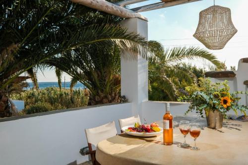 un tavolo con un cesto di frutta e una bottiglia di vino di Golden Beach Studios & Suites a Città di Tinos