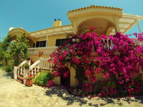 una casa con fiori rosa su un lato di Appartamenti Angelika a Perdika