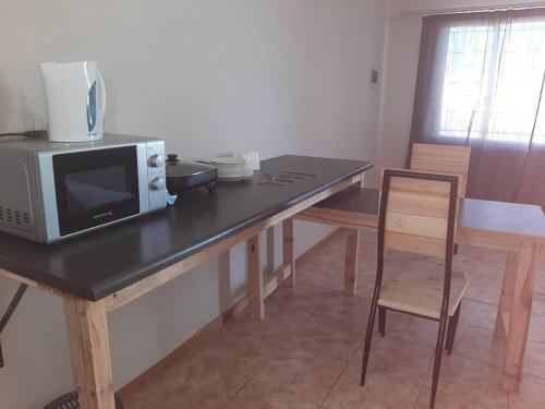 eine Küche mit einem Tisch, einer Mikrowelle und einem Stuhl in der Unterkunft OrbanLife Lite Keetmanshoop in Keetmanshoop