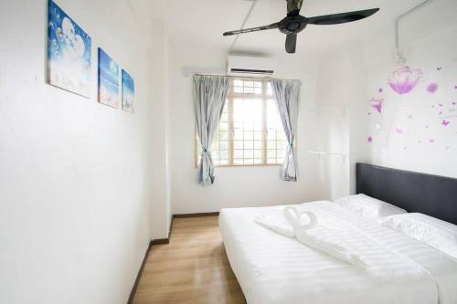 a bedroom with a white bed and a window at Santorini Home in Tanjung Bungah