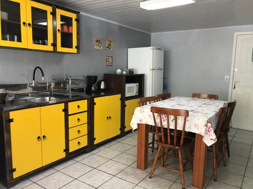 a kitchen with yellow cabinets and a table with chairs at Casa no Centrinho 100m do Mar in Bombinhas