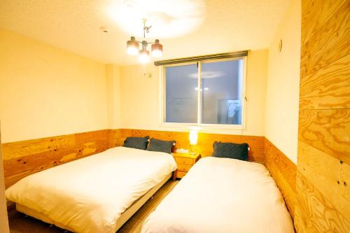 two beds in a room with a window at kODATEL コダテル 札幌大通公園 101 in Sapporo