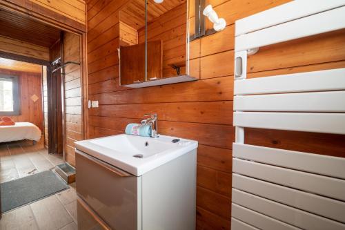 a bathroom with a white sink and wooden walls at Chalet des Ecureuils - 3 étoiles au pied des pistes in Les Angles