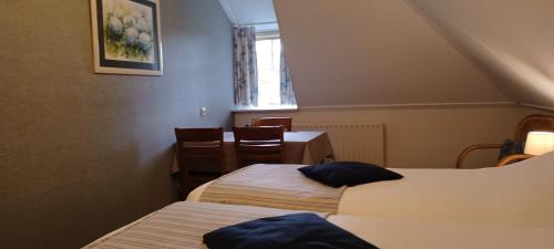 a room with two beds and a table and a window at Pension De Hoestinkhof in Markelo