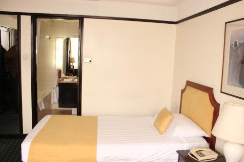 a hotel room with a bed and a phone on a table at Nairobi Safari Club by Swiss-Belhotel in Nairobi