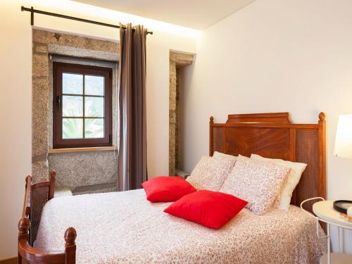 a bedroom with a bed with red pillows on it at Cerca dos Passais in Entre Ambos os Rios